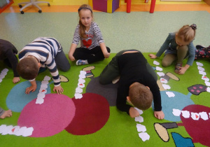 Czwórka dzieci przelicza szablony mapy Polski ułożone w rzędzie, odwracają trzeci z kolej.